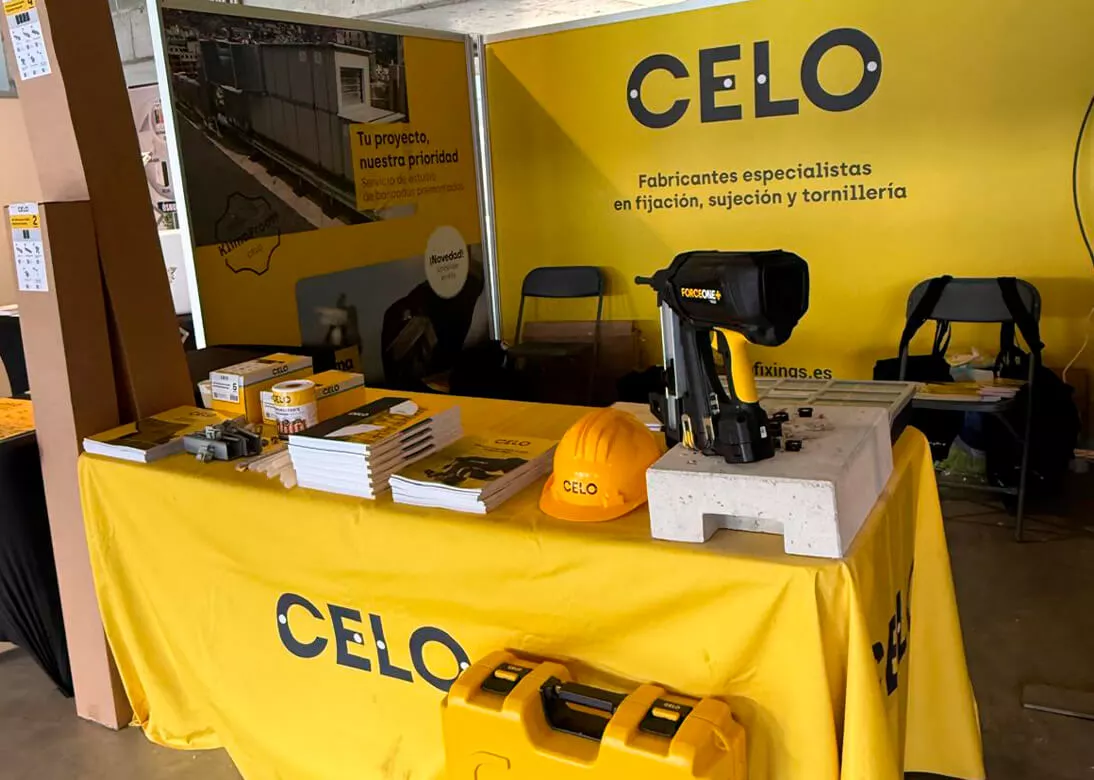 Stand-de-CELO-en-la-feria-Auna-Partner-Day-con-mostrador-amarillo-con-una-pistola-de-clavos-y-otros-productos